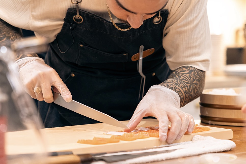 Chef Logan scoring salmon for an omakase course.