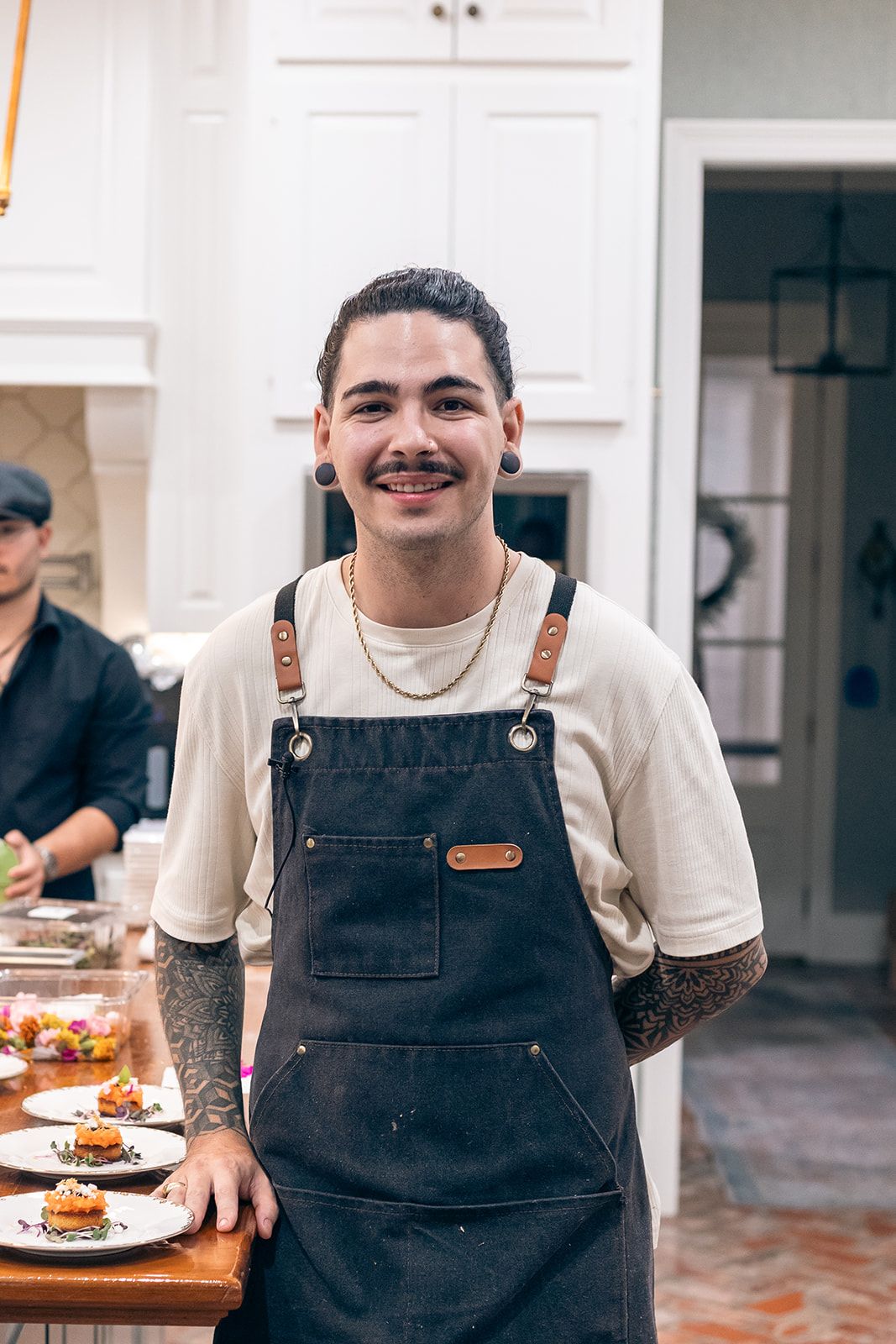 Chef Logan Corpora smiling beside a row of plated courses.
